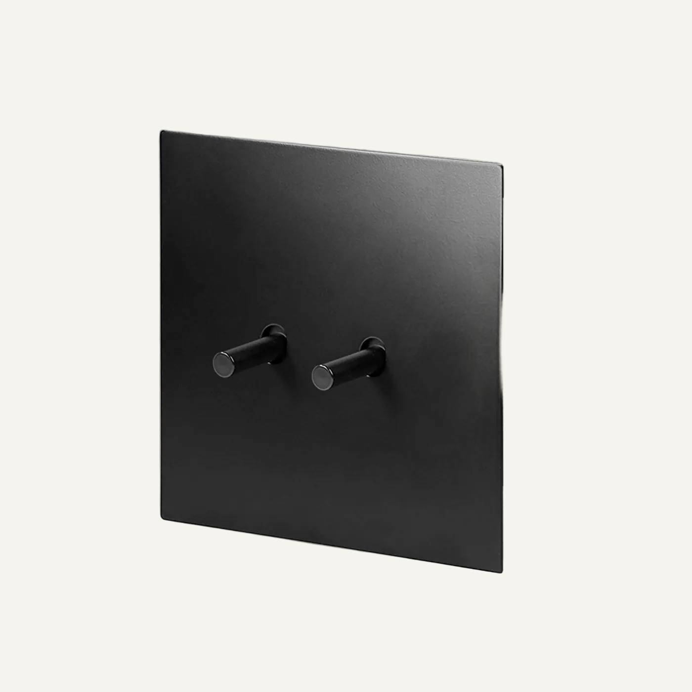 Black square wall plate with three knobs on a light gray background