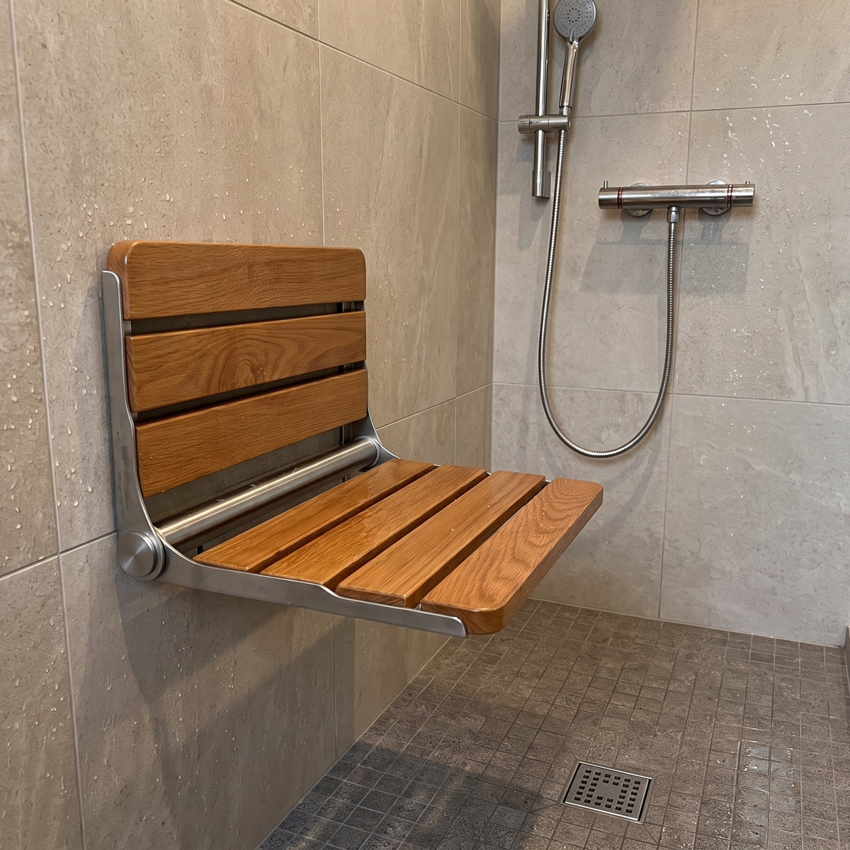 Luxworth Oak folding shower seat with wooden finish, compact design, and sturdy metal frame for safe bathroom seating.