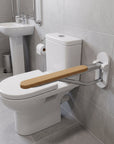 Foldable wooden and satin aluminum toilet grab rail from Luxworth, mounted on a bathroom wall for safety and support.